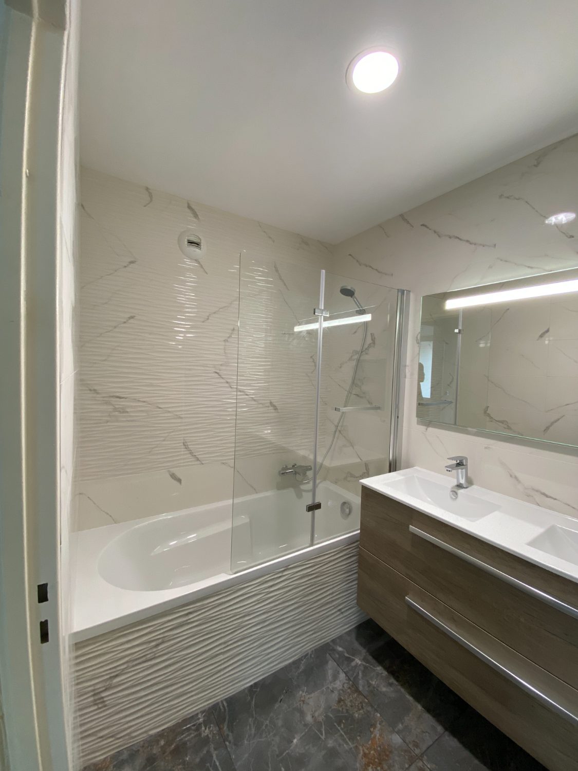 Salle de bain rénovée avec baignoire et carreaux marbrés en relief